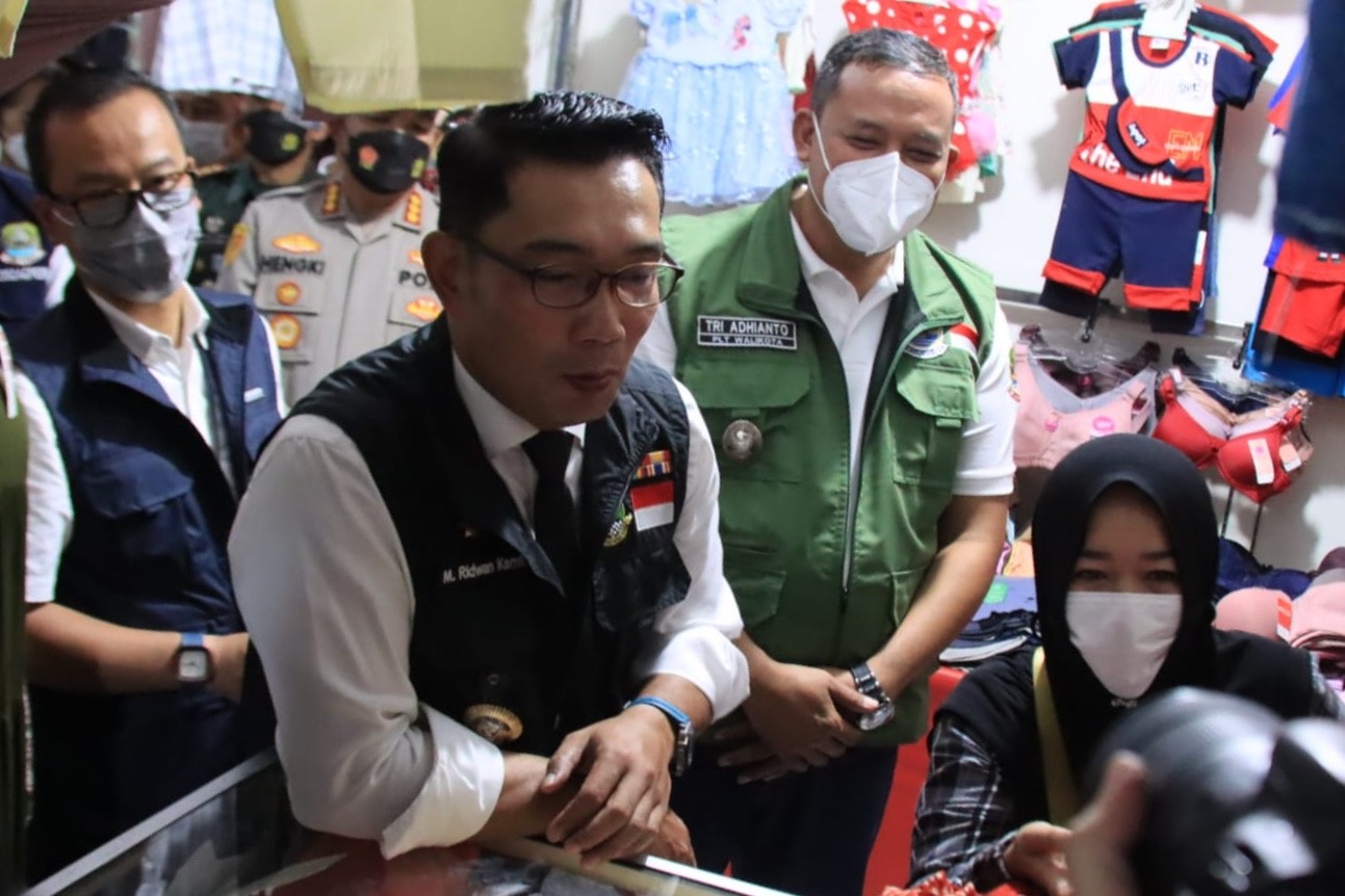 Gubernur Jawa Barat Ridwan Kamil didamping Plt Walikota Bekasi Tri Adhianto saat menemui seorang pedagang pasar rakyat jabar juara yang baru diresmikan di Harapan Jaya, Bekasi Utara, Rabu (20/4/2022).